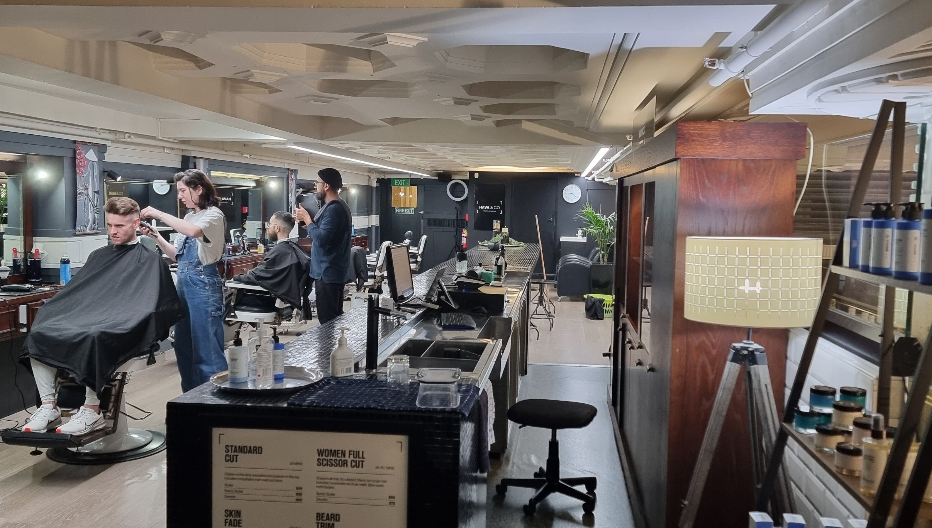 Barbers trimming hair at Hava & Co, Auckland, NZ, in a stylish interior with modern decor.