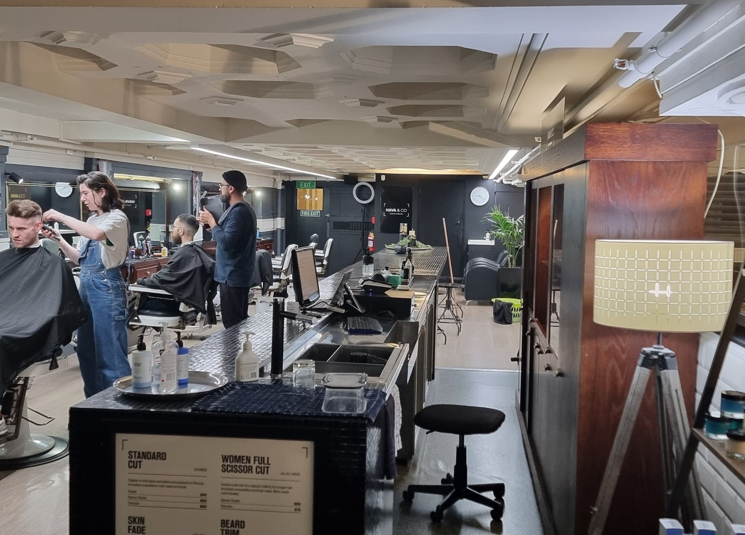 Barbers trimming hair at Hava & Co, Auckland, NZ, in a stylish interior with modern decor.
