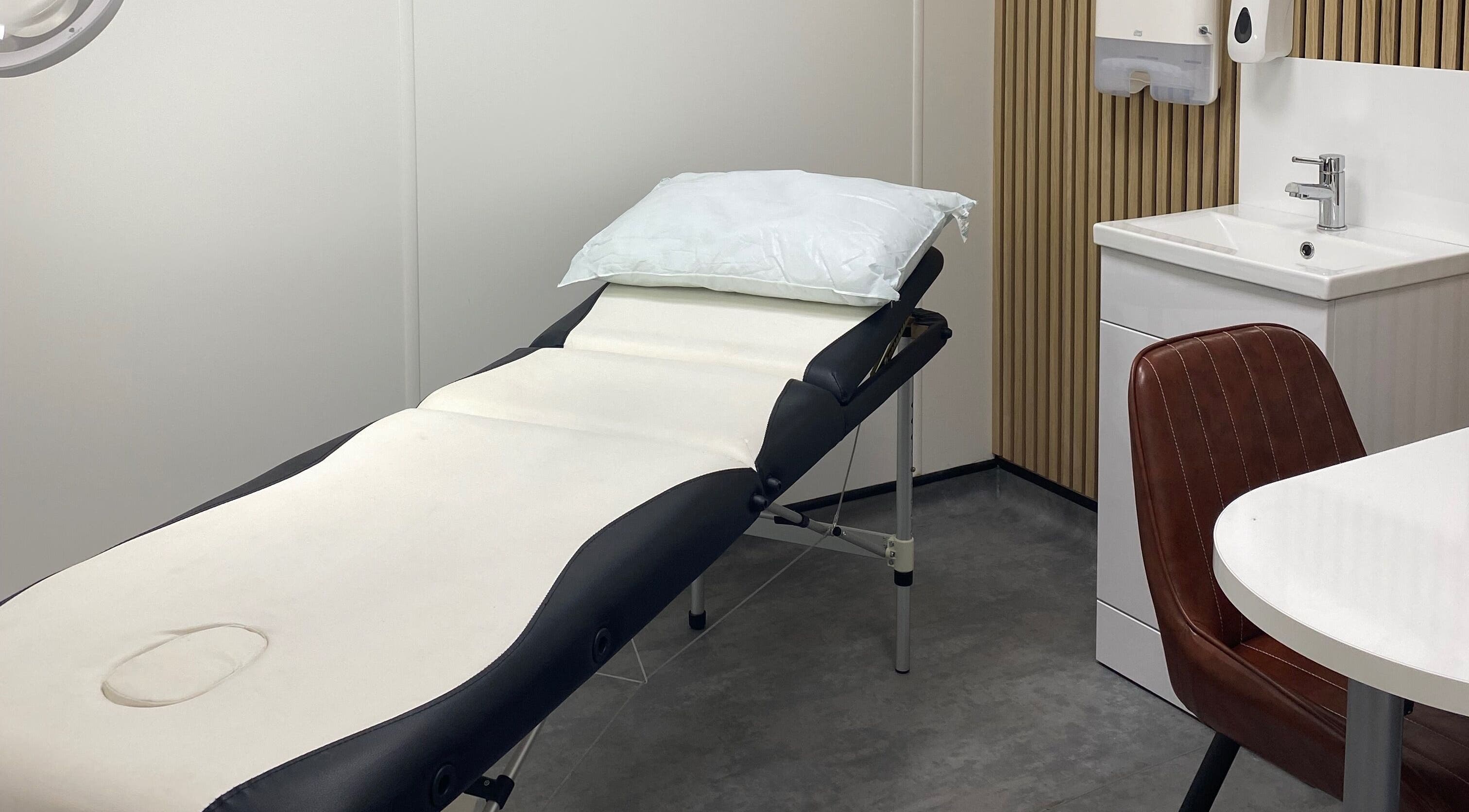 Modern treatment room at MP Skinthetics in Havant, England, featuring a comfortable therapy bed and sink.