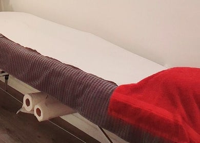 Cozy massage table covered with vibrant red towel at Pupa Beauty Body Treatments, Weeting, England, GB.