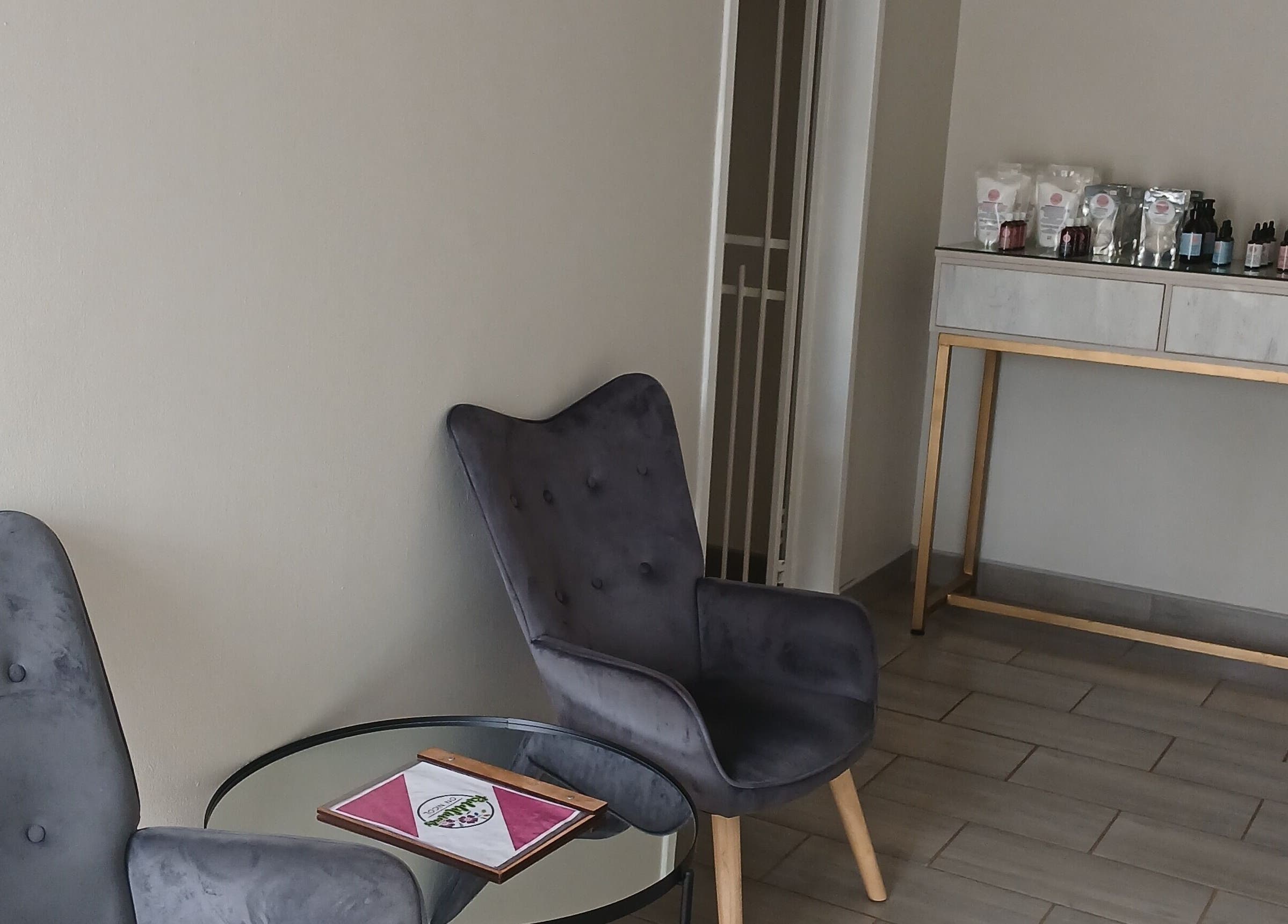 Relaxing lounge area at SN BEAUTY LAB, Johannesburg, Gauteng, ZA with grey chairs and a product display.