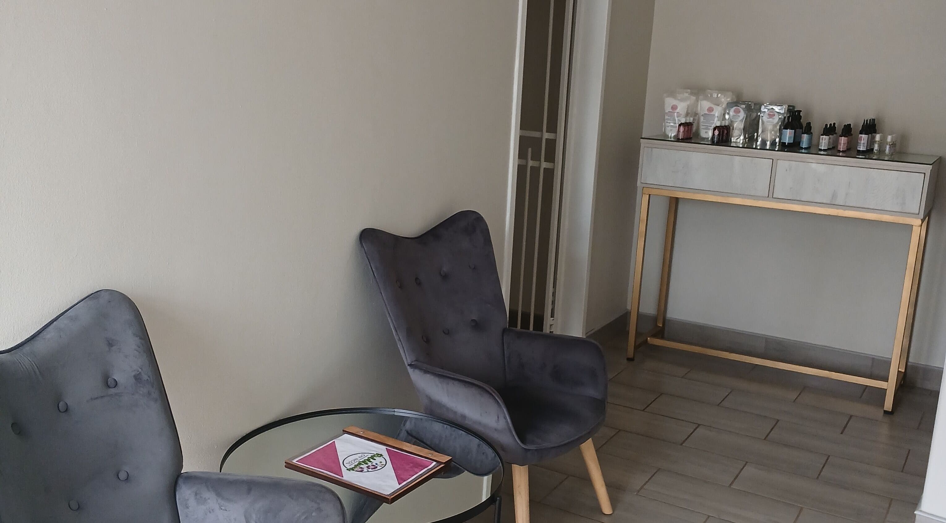 Relaxing lounge area at SN BEAUTY LAB, Johannesburg, Gauteng, ZA with grey chairs and a product display.
