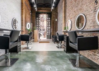 Interior moderno de Chande Hair Stylist - Lab129 en Barcelona, Catalunya, ES con sillas negras y espejos iluminados.