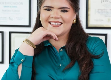 Smiling professional at Valórate Aesthetic, Gurabo, Gurabo, PR, with framed certificates in the background.