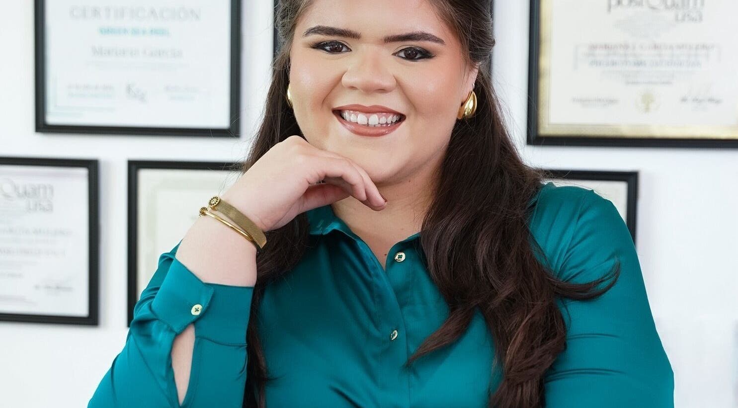 Smiling professional at Valórate Aesthetic, Gurabo, Gurabo, PR, with framed certificates in the background.