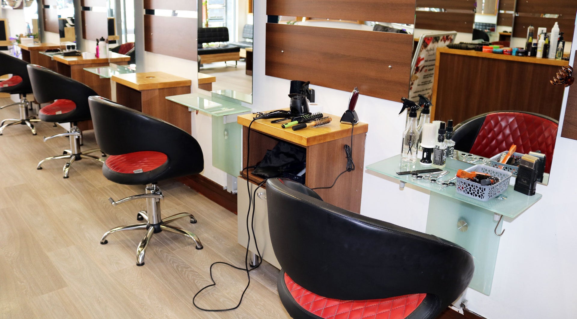 Modern styling stations at Sunset Hair Salon, Dublin, Ireland, IE, showcasing sleek black and red salon chairs.