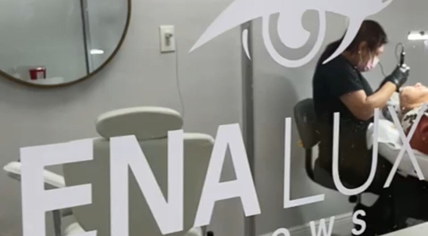 Profesional realiza tratamiento en Ena Luxe Brows, Miami, Florida, US, con espejo decorativo al fondo.