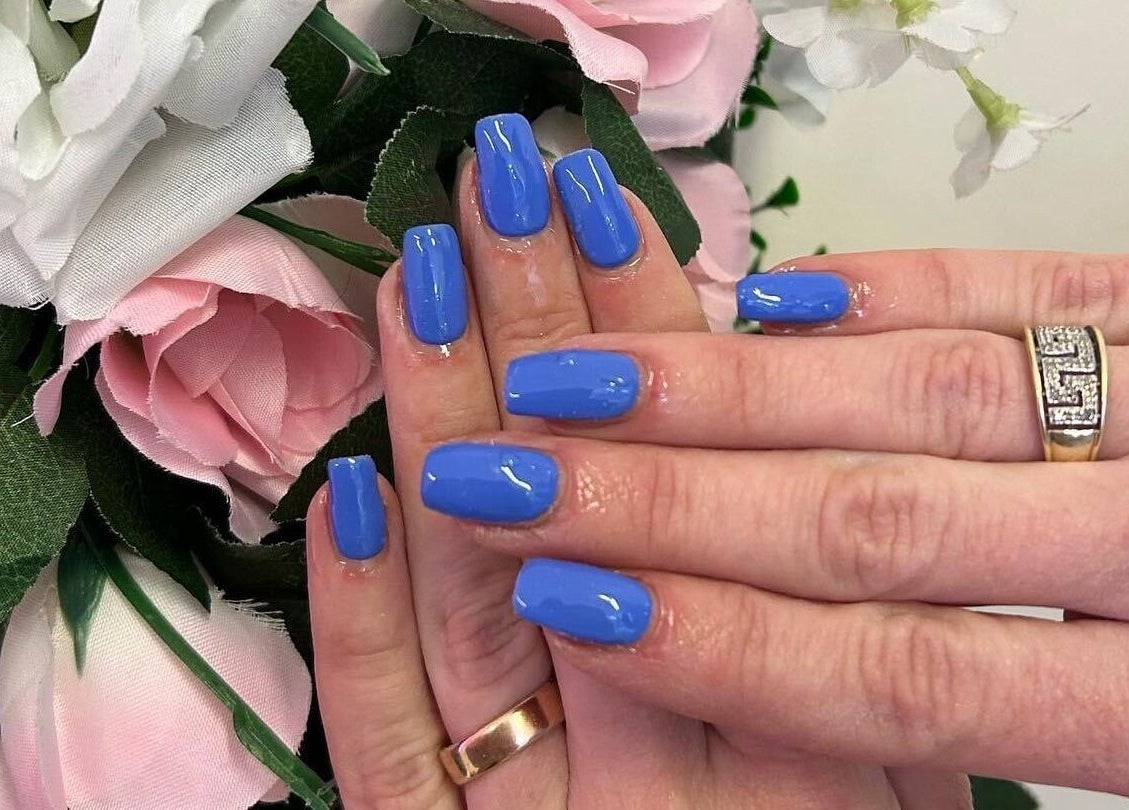 Elegant blue manicured nails with floral backdrop at Jessica Jay Salon, Perth, Scotland, GB.