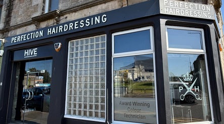 Exterior of Perfection Hairdressing in Kirkcaldy, Scotland, GB, highlighting salon signage and glass windows.