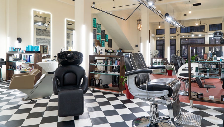 Κομψό εσωτερικό του Koureio Barbershop στην Ιεράπετρα, GR με καρέκλες και προϊόντα περιποίησης.