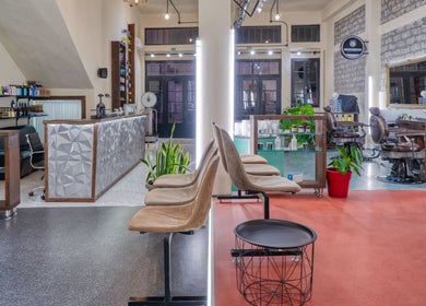 Εσωτερικό του Koureio Barbershop στην Ιεράπετρα, GR με σύγχρονη διακόσμηση και άνετα καθίσματα.
