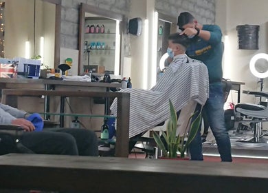 Κουρέας στο Koureio Barbershop στην Ιεράπετρα, GR, κόβει μαλλιά σε πελάτη με προσοχή στη λεπτομέρεια.