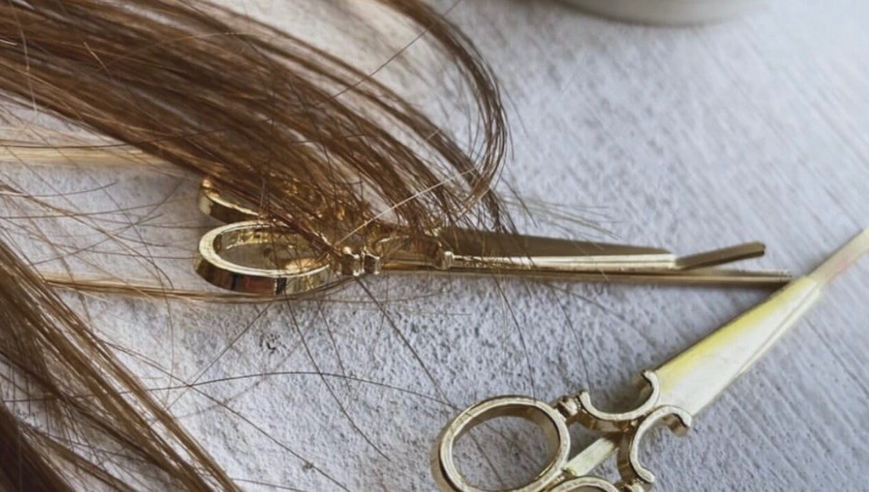 Elegant golden scissors with hair strands at Root & Remedy, Southampton, England, GB.