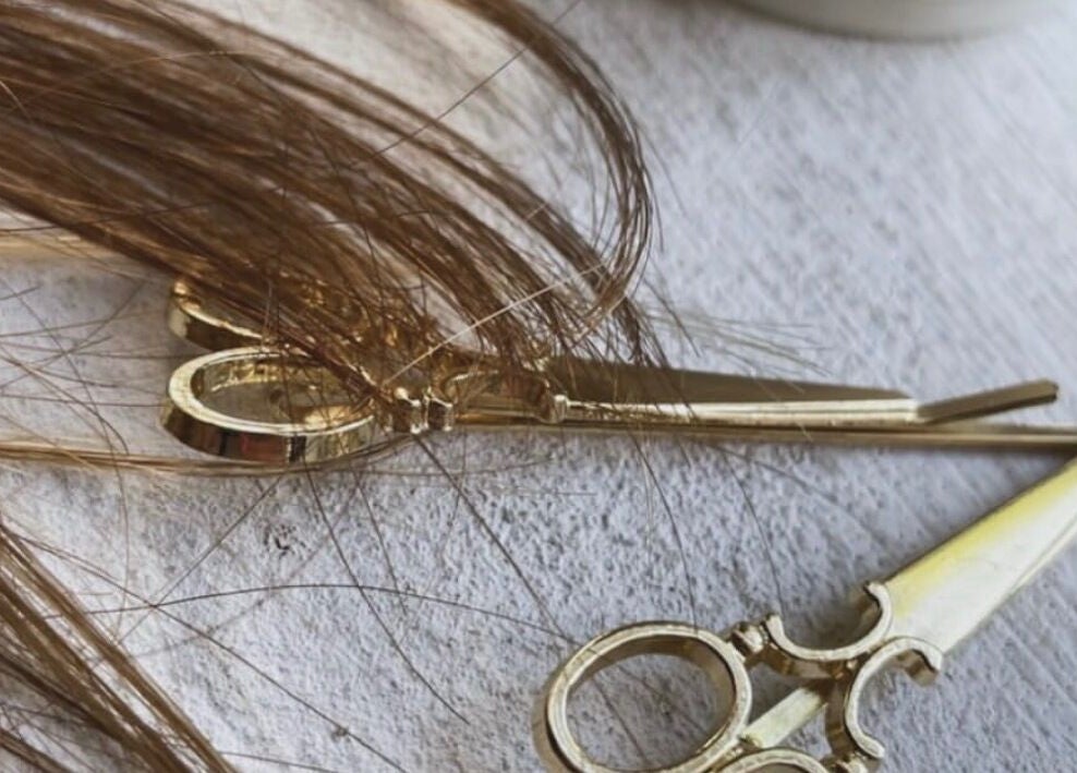 Elegant golden scissors with hair strands at Root & Remedy, Southampton, England, GB.