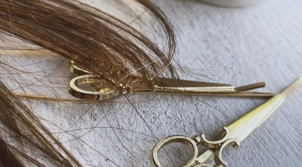 Elegant golden scissors with hair strands at Root & Remedy, Southampton, England, GB.