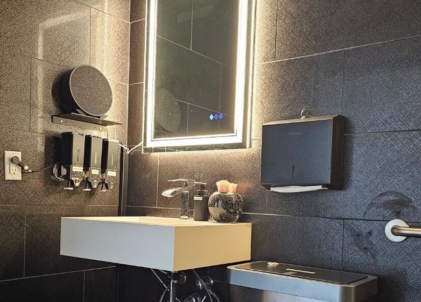 Modern bathroom vanity at Ombré Terrace ™, Torrance, California, US with illuminated mirror and dispenser.
