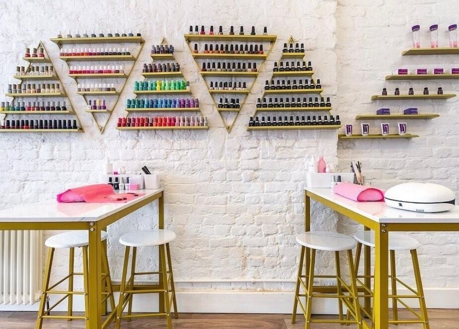 Elegant nail bar at Arta Beauty Clinic, London, England, GB, featuring vibrant polish displays on white brick walls.