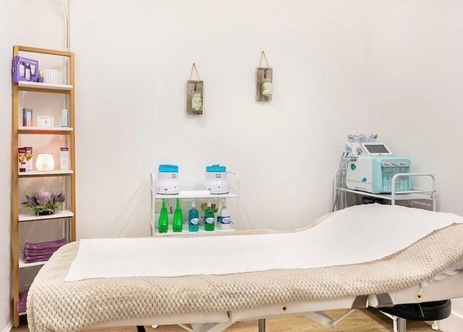 Calming treatment room at Arta Beauty Clinic, London, England, GB with massage bed and skincare products.
