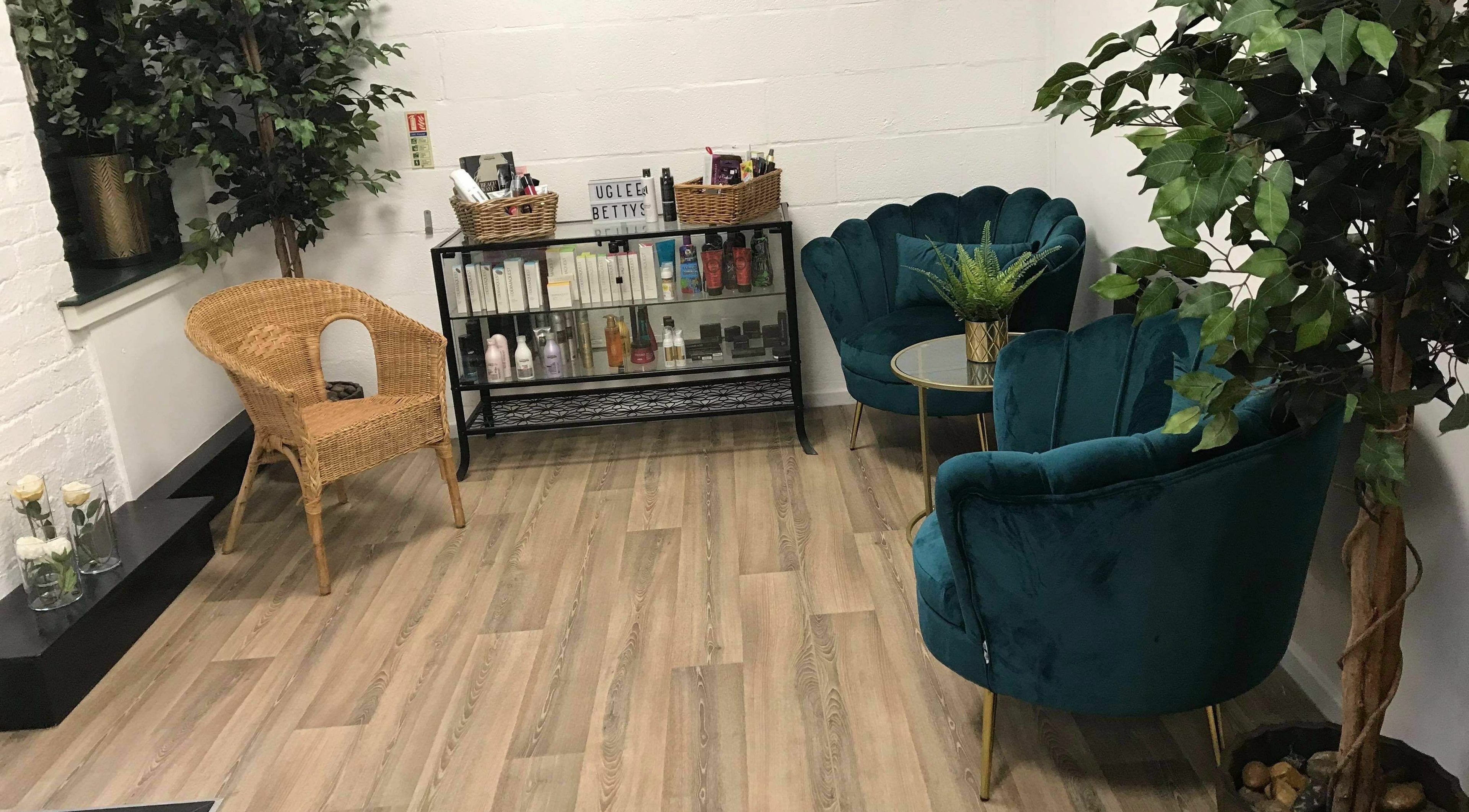 Chic waiting area at Uglee Betties, Carlisle, England, GB with plush chairs and product display.