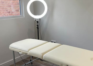 A serene treatment room at LR Skin & Aesthetics in Leicester, England, GB, featuring a massage table and ring light.