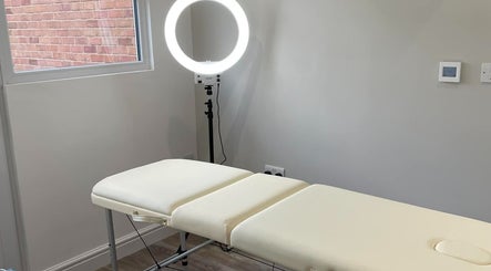 A serene treatment room at LR Skin & Aesthetics in Leicester, England, GB, featuring a massage table and ring light.