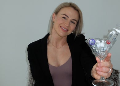Smiling professional at LR Skin & Aesthetics in Leicester, England, holding beauty vials in a glass.