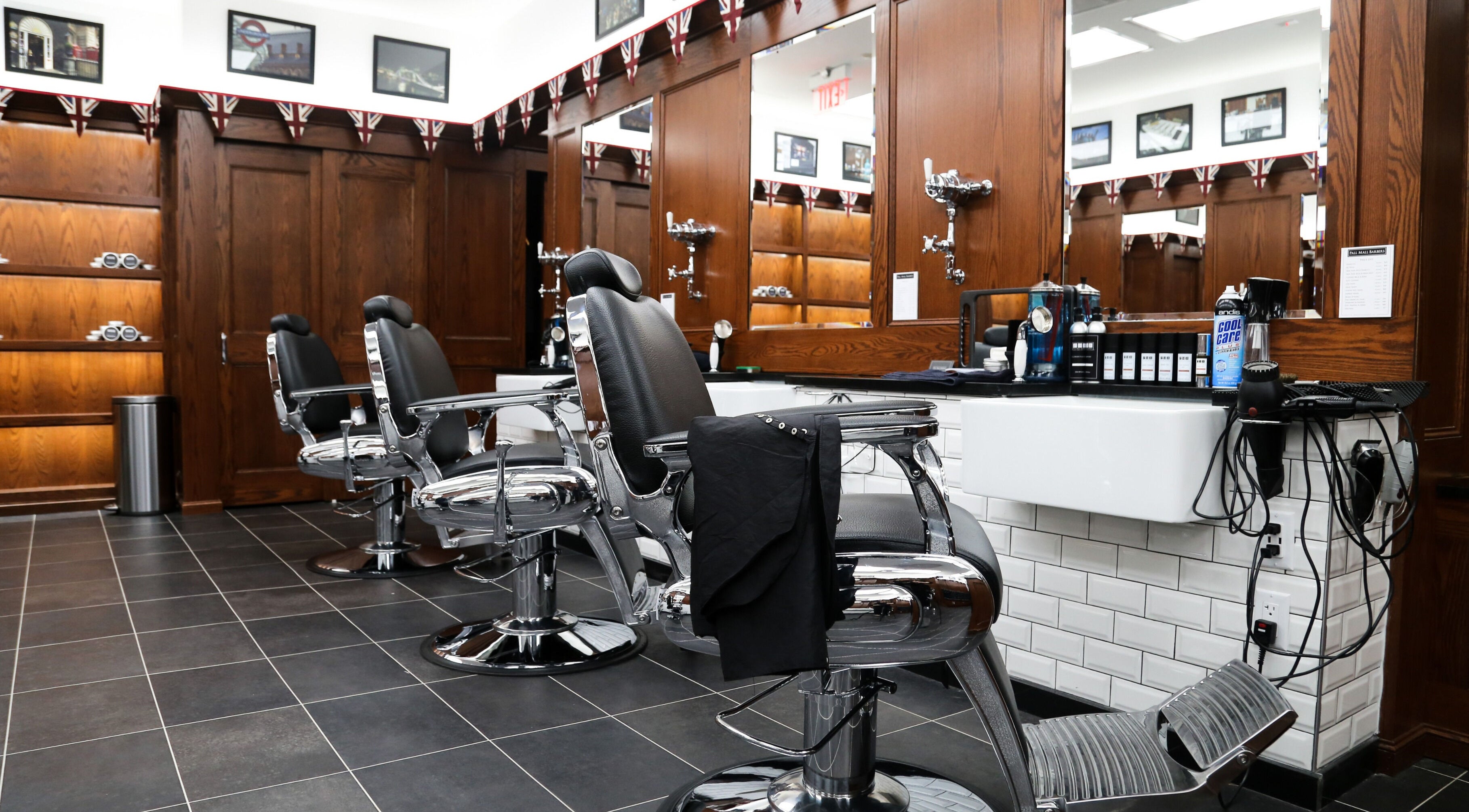 Elegant interior of Pall Mall Barbers NYC in New York showing barber chairs and wooden decor.