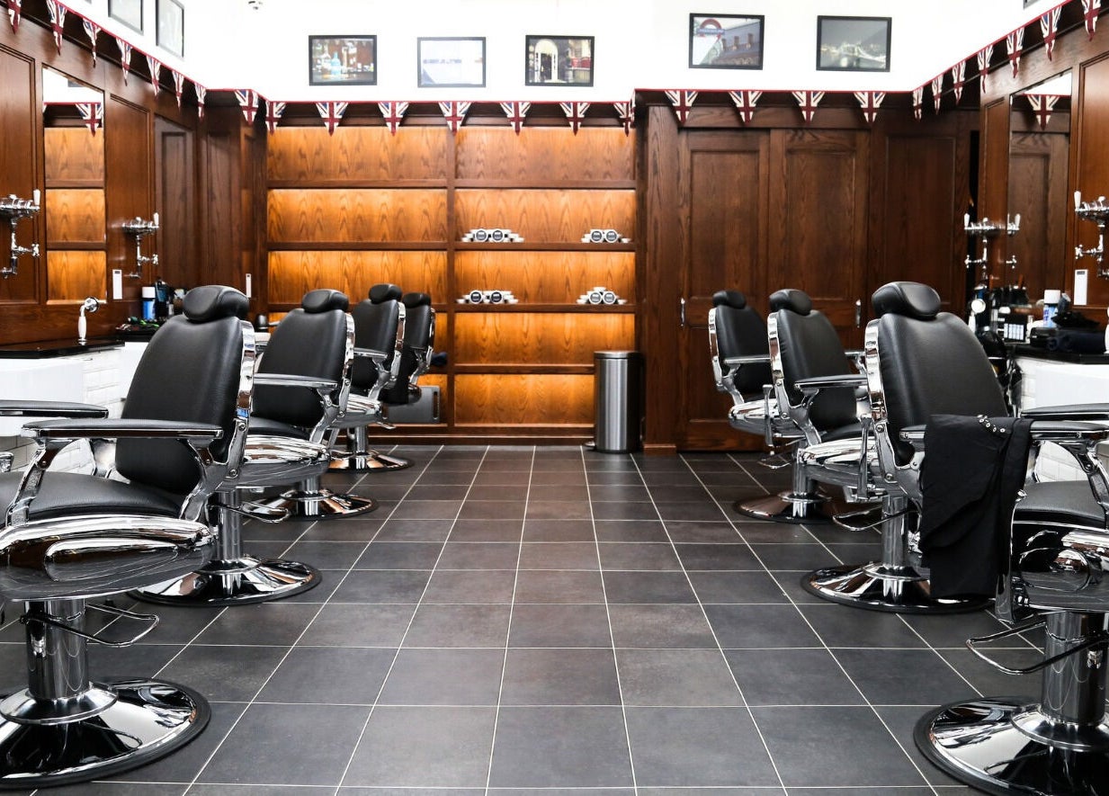 Elegant barber chairs at Pall Mall Barbers NYC, New York, New York, US, with wood accents and tiled floor.