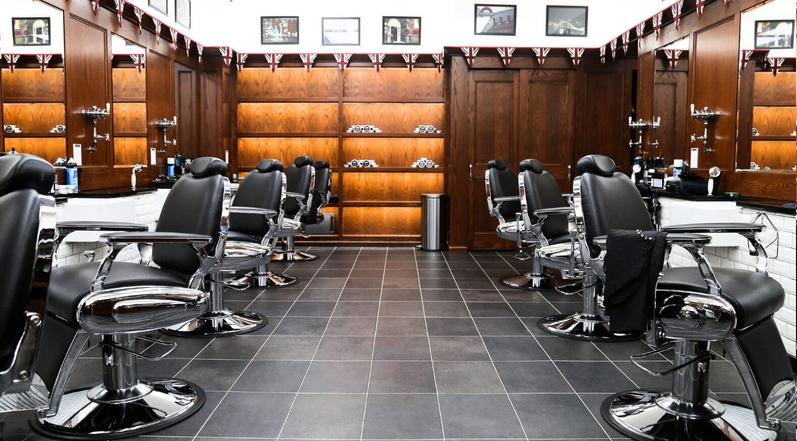 Elegant barber chairs at Pall Mall Barbers NYC, New York, New York, US, with wood accents and tiled floor.