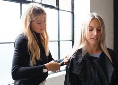 Stylist at Salon Chatsworth Road E5 cutting hair in London, England, GB with natural light from window.