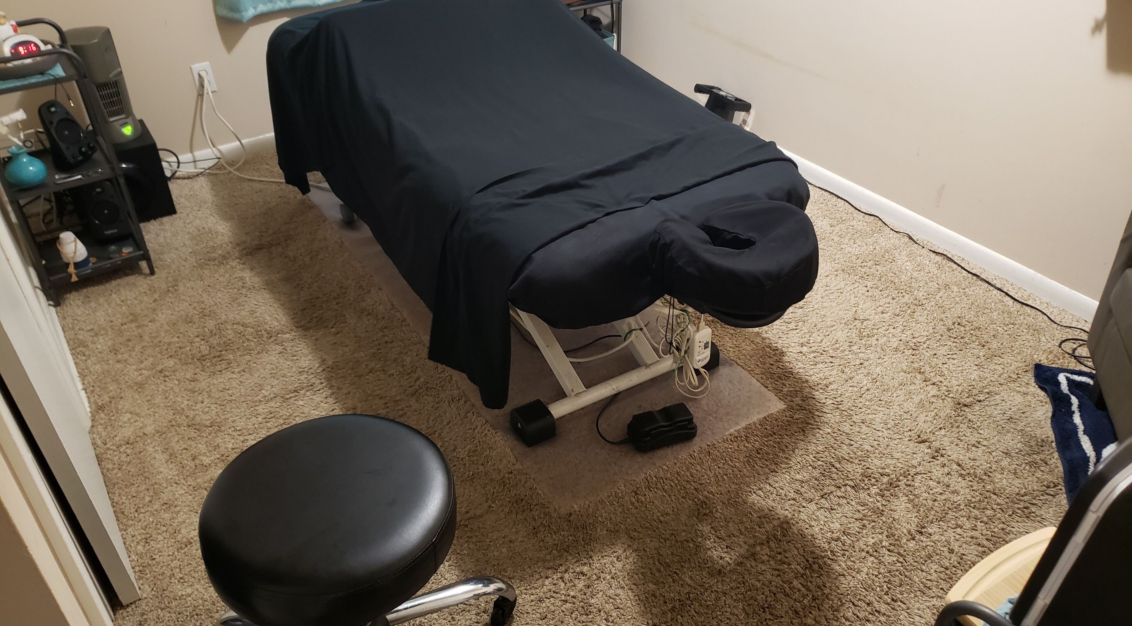 Cozy massage room at These Hands Thera Massage in Tulsa, Oklahoma, US with a treatment table and stool.