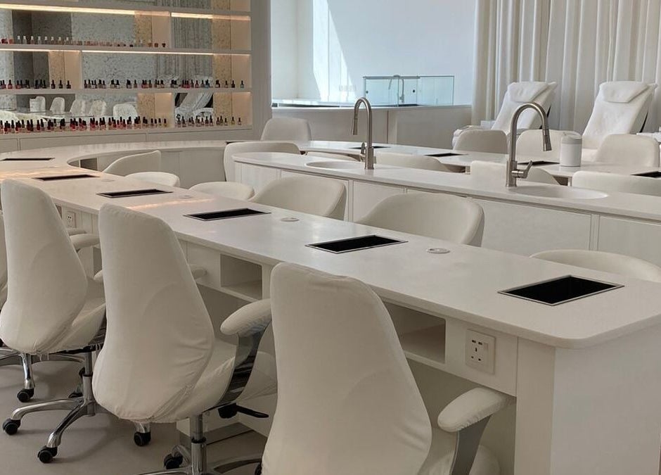 Modern nail station at Yin Salon and Spa in Riyadh, SA, featuring sleek white chairs and countertops.