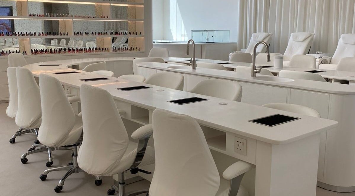 Modern nail station at Yin Salon and Spa in Riyadh, SA, featuring sleek white chairs and countertops.