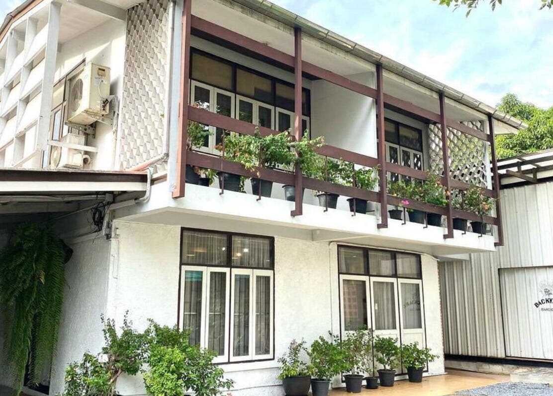 CUCHU Hair Design's stylish exterior with lush greenery in Bangkok, TH, showcasing elegance and charm.