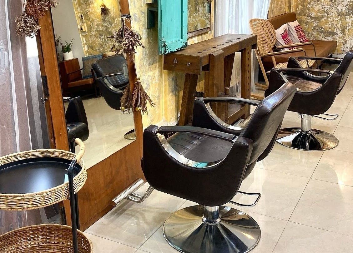 Elegant salon setup at CUCHU Hair Design in Bangkok, TH showcasing modern chairs and rustic decor.