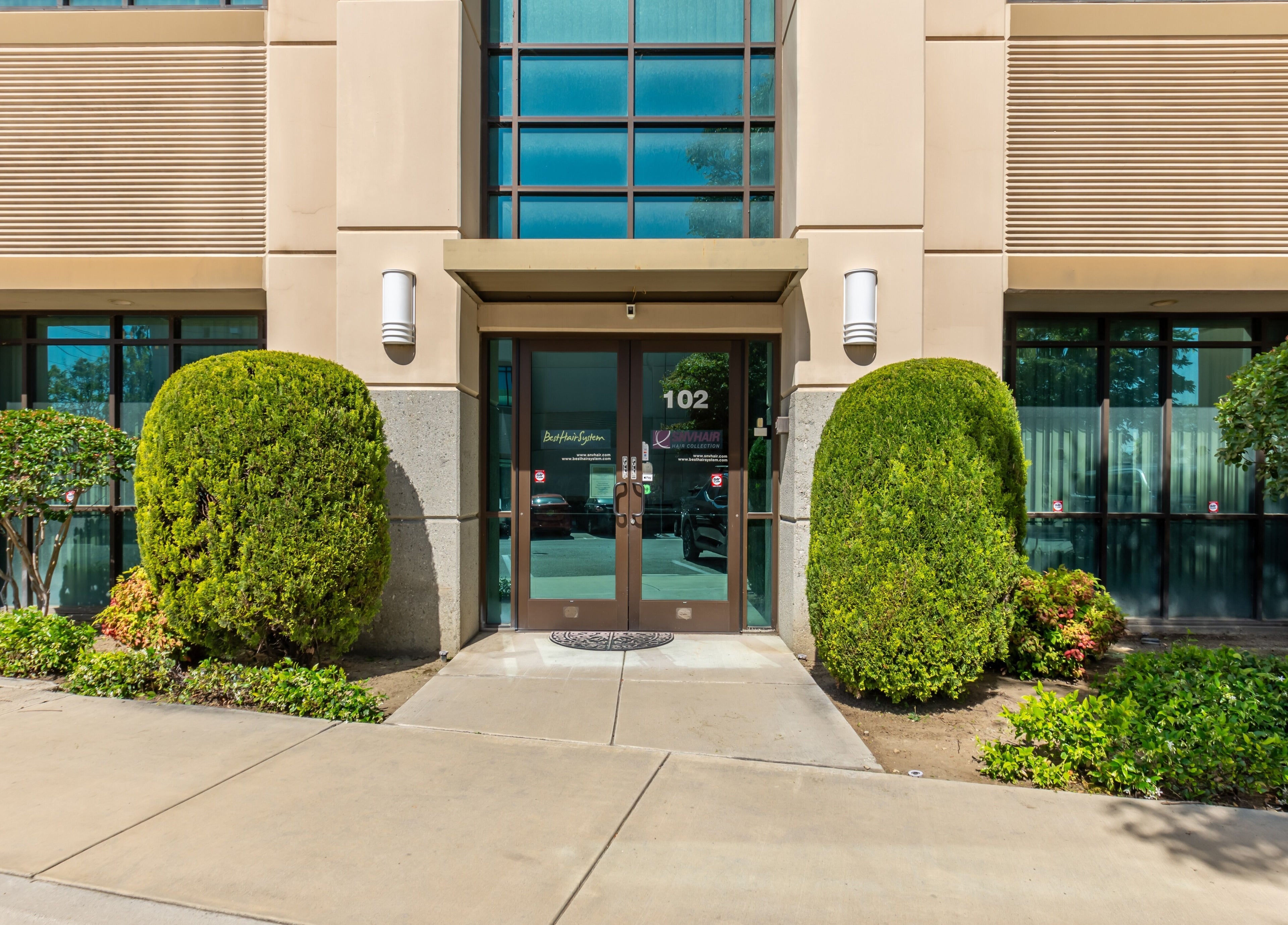 Entrance of Best Hair System in Rancho Cucamonga, California, US, featuring lush greenery and modern design.