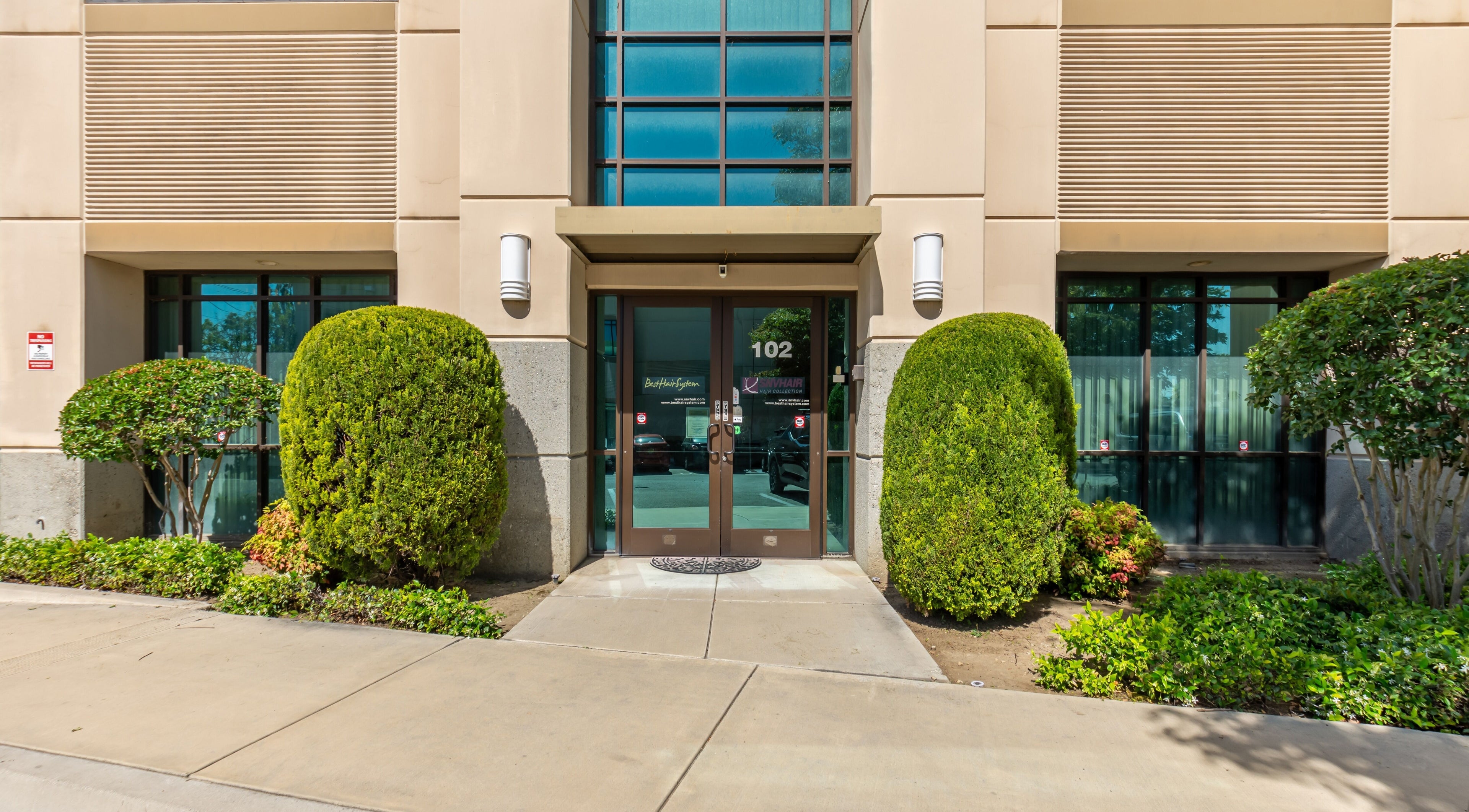 Entrance of Best Hair System in Rancho Cucamonga, California, US, featuring lush greenery and modern design.