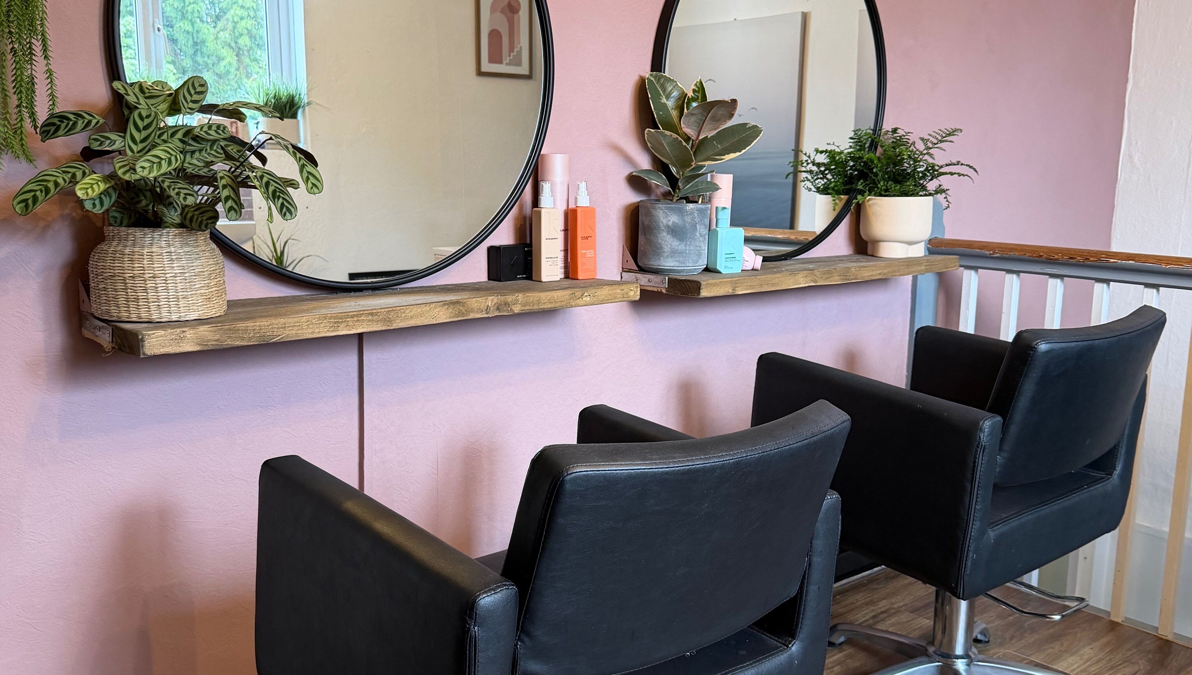 Modern salon chairs and mirrors at The Colour Room, Alcester, England, GB, with plants and beauty products.