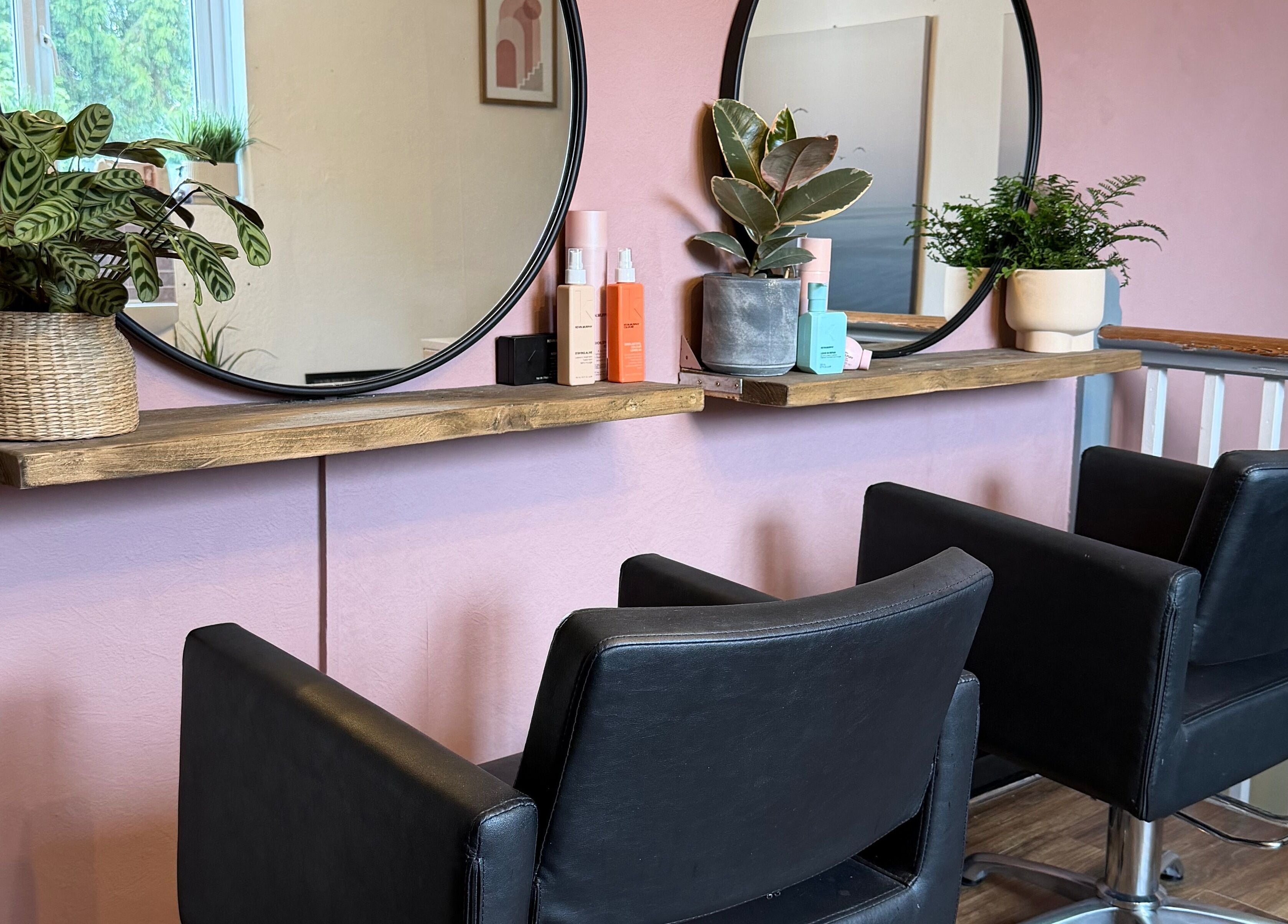 Modern salon chairs and mirrors at The Colour Room, Alcester, England, GB, with plants and beauty products.