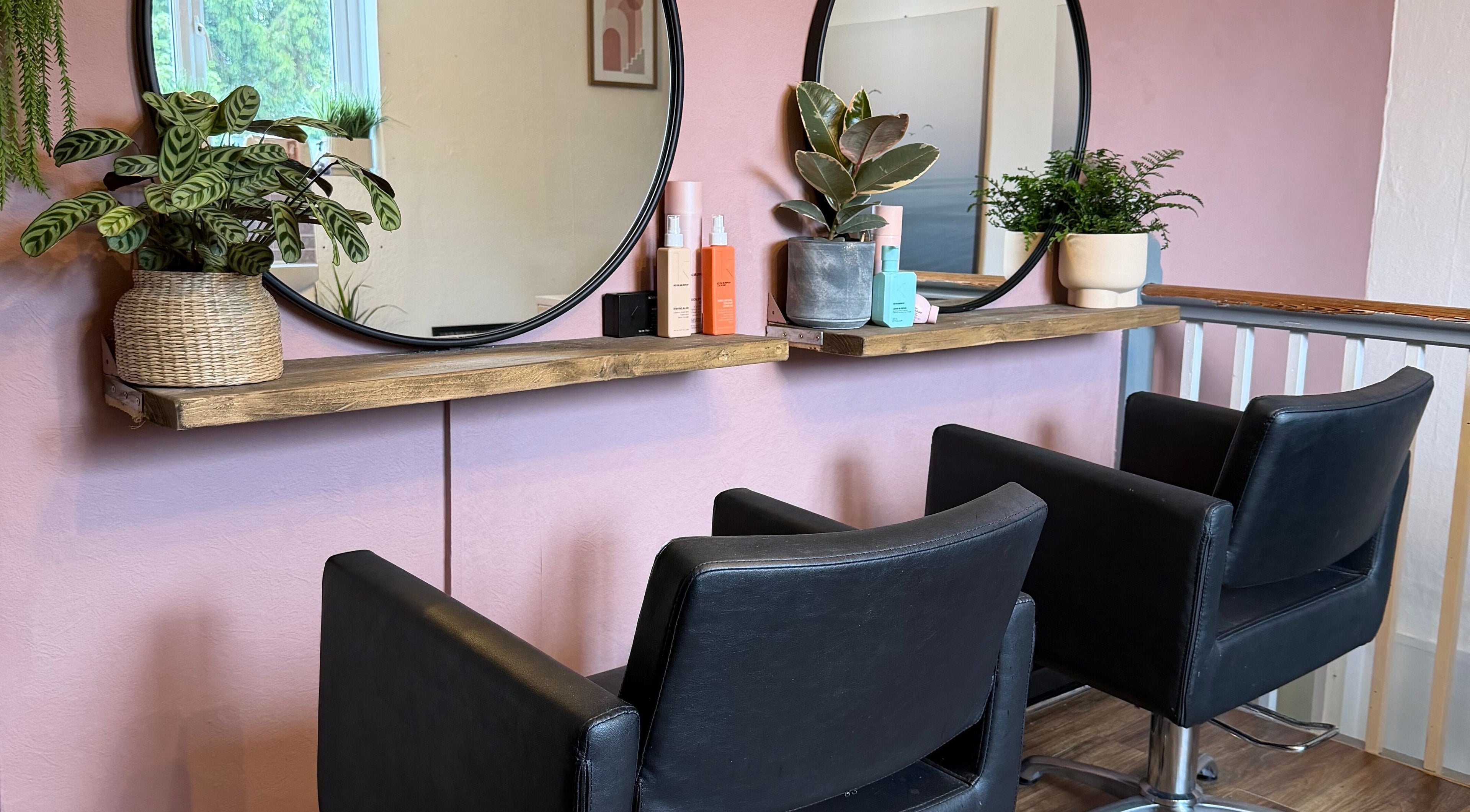 Modern salon chairs and mirrors at The Colour Room, Alcester, England, GB, with plants and beauty products.
