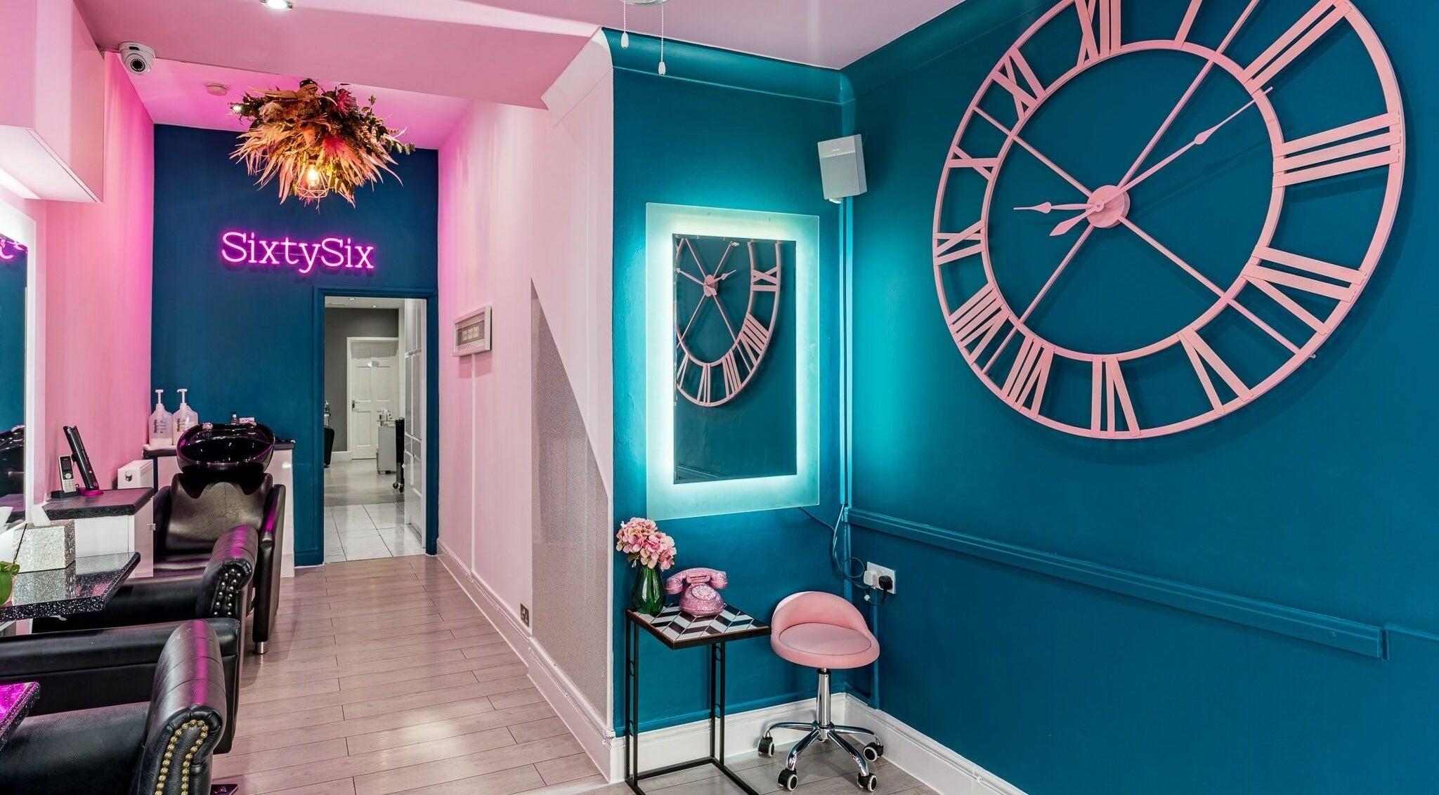 Interior of SixtySix salon in Ilford, England, GB with stylish decor and a large wall clock.