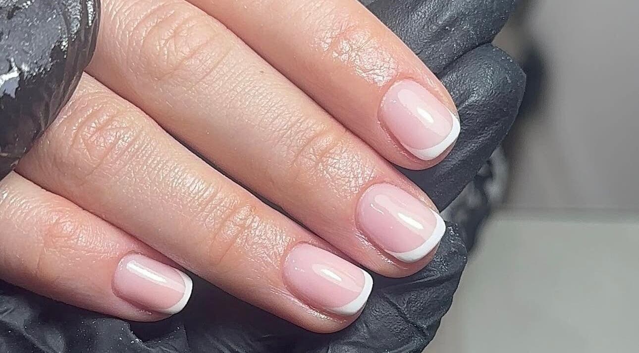 French manicure at Polished by Izzy Mae in Rugby, England, GB, showcasing elegant hand with black glove.