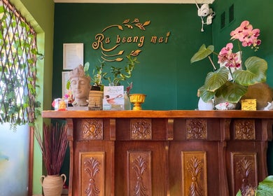 Reception at Rabeang Mai Thai Massage Therapy, Cape Town, with lush greenery and a serene Buddha statue.