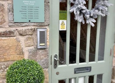 Front entrance of Dawn Furness at Okra Salon in Bedlington, England, GB featuring rustic decor and greenery.