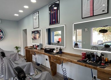 Interior moderno de la barbería BladesColor Reus, Reus, Catalunya, ES, con sillones y espejos iluminados.