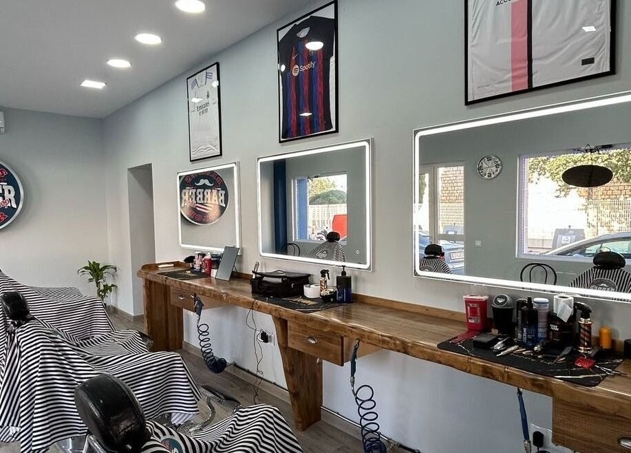 Interior moderno de la barbería BladesColor Reus, Reus, Catalunya, ES, con sillones y espejos iluminados.