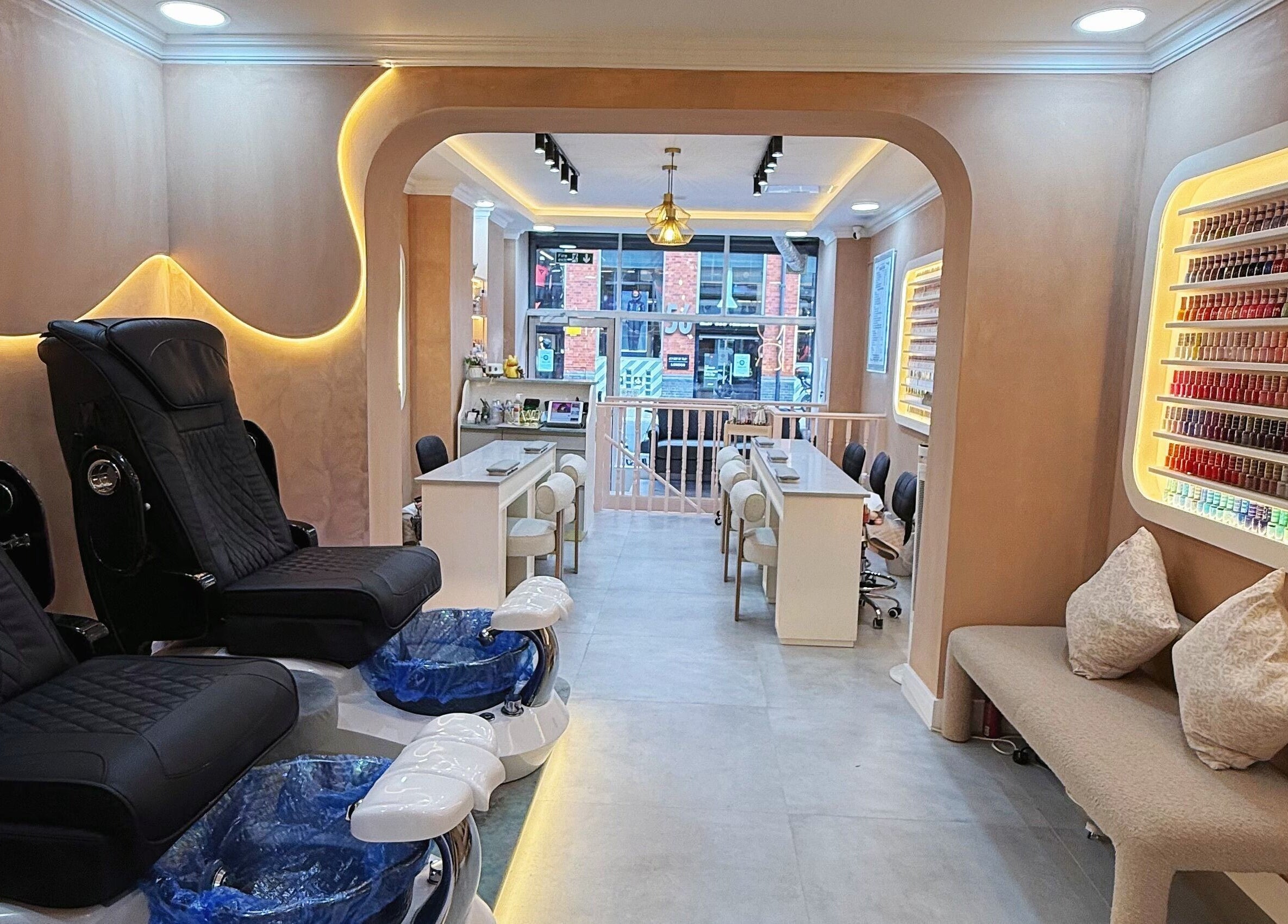 Luxurious interior of Natural Nails in London, England, GB featuring plush chairs and a colorful nail polish display.