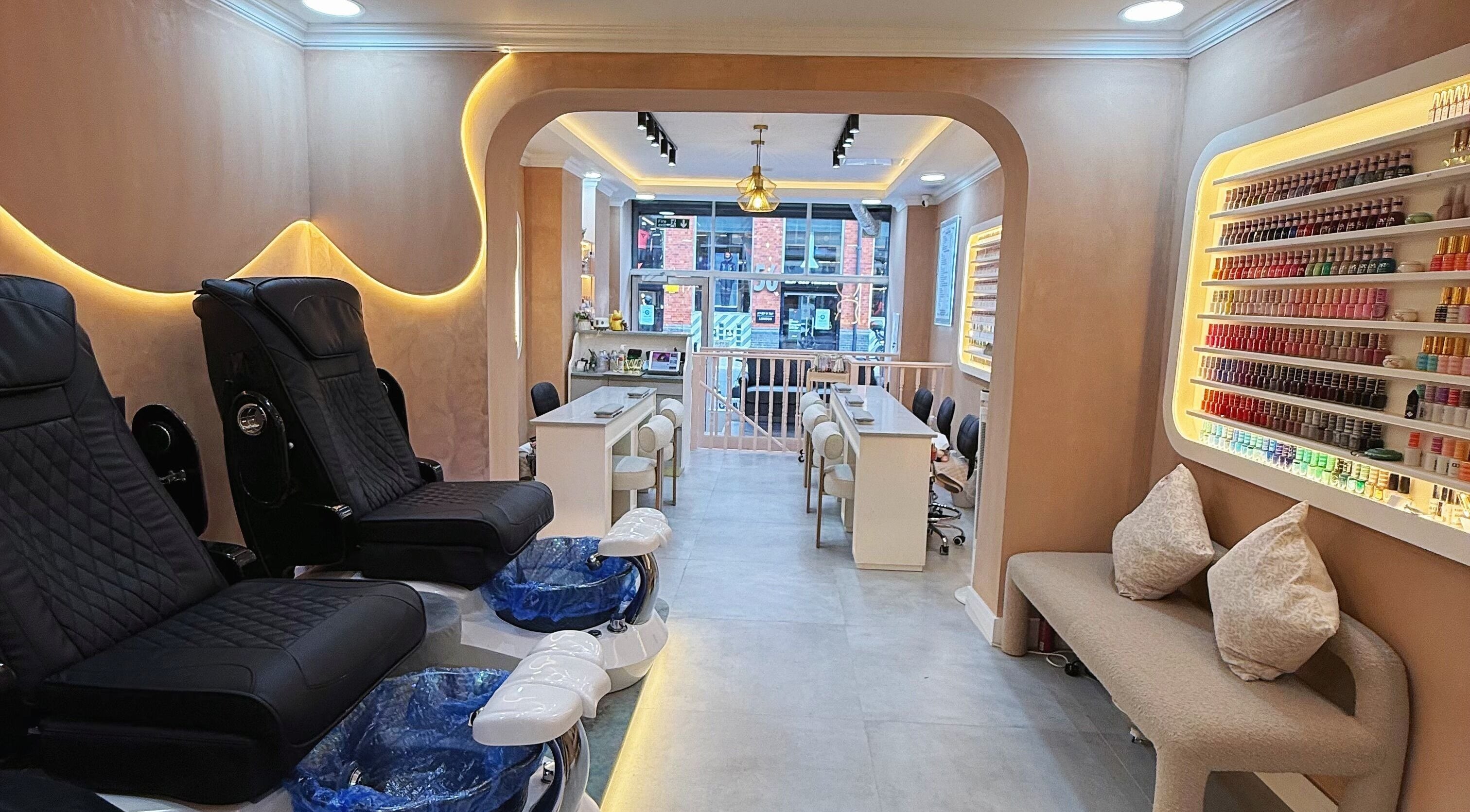 Luxurious interior of Natural Nails in London, England, GB featuring plush chairs and a colorful nail polish display.