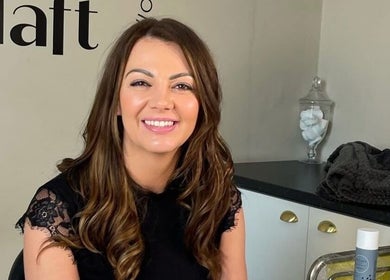 Smiling client at SOMA Skin Clinic in Kidderminster, England, surrounded by skincare products.