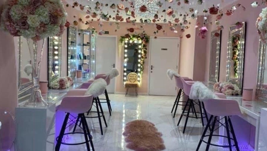 Elegant beauty salon interior at HMAKE, Stockport, England, GB with pink chairs and floral decor.